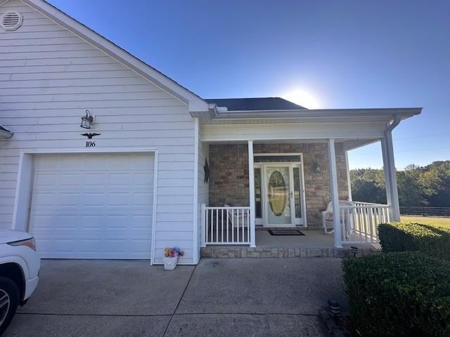 view of front of home with concrete driveway, a porch, and a garage