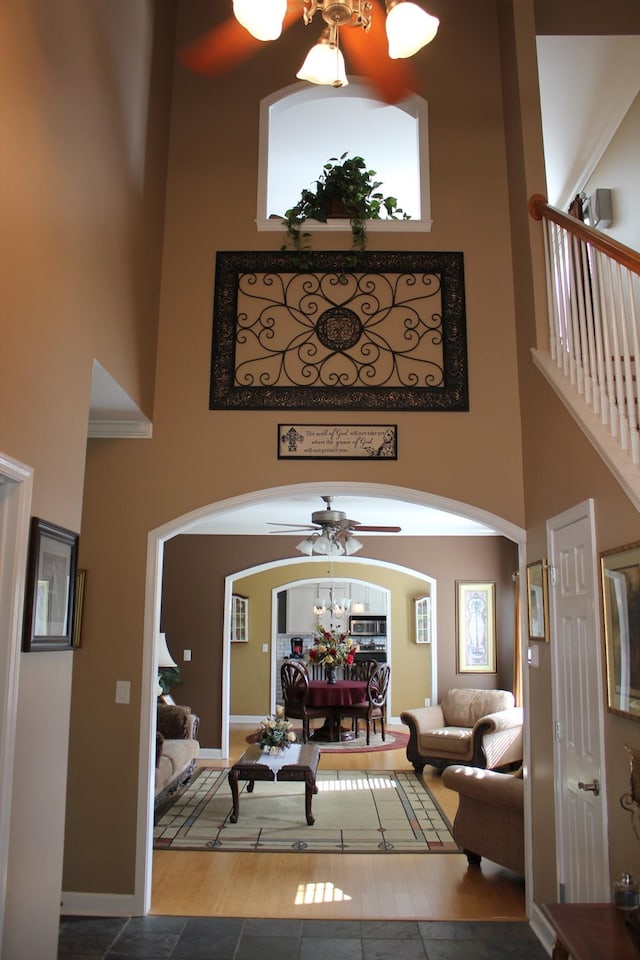 living room with a chandelier, a towering ceiling, arched walkways, and baseboards