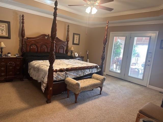 bedroom featuring ornamental molding, a tray ceiling, light colored carpet, and access to exterior