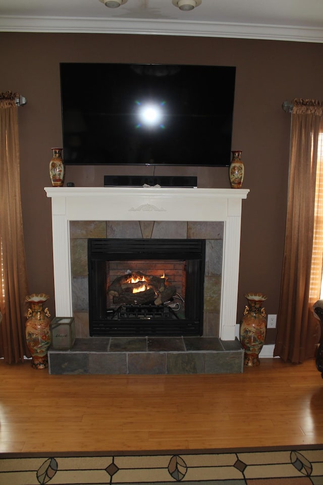 room details featuring a tile fireplace, wood finished floors, baseboards, and ornamental molding
