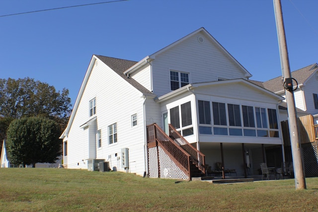 rear view of property with a yard, a sunroom, stairs, and central AC