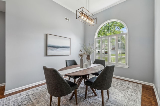 dining area featuring baseboards, ornamental molding, an inviting chandelier, visible vents, and wood finished floors