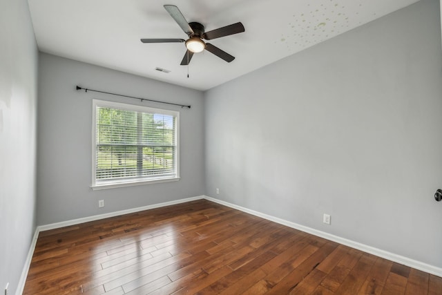 empty room featuring ceiling fan, baseboards, visible vents, and wood finished floors
