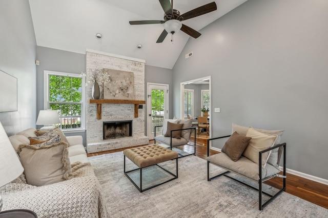 living room featuring wood finished floors, high vaulted ceiling, visible vents, baseboards, and a large fireplace