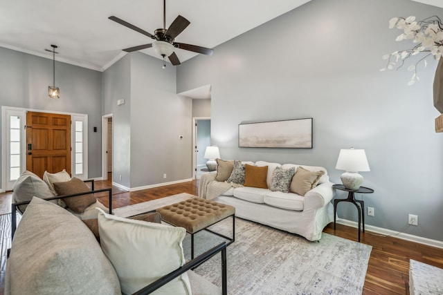 living room featuring wood finished floors, a towering ceiling, ceiling fan, crown molding, and baseboards