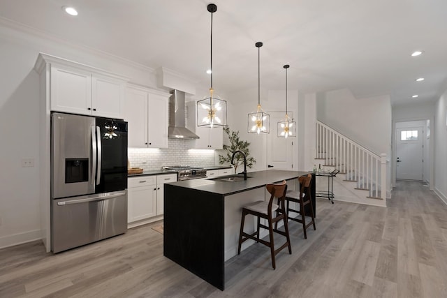 kitchen featuring a sink, dark countertops, wall chimney exhaust hood, stainless steel fridge with ice dispenser, and decorative backsplash