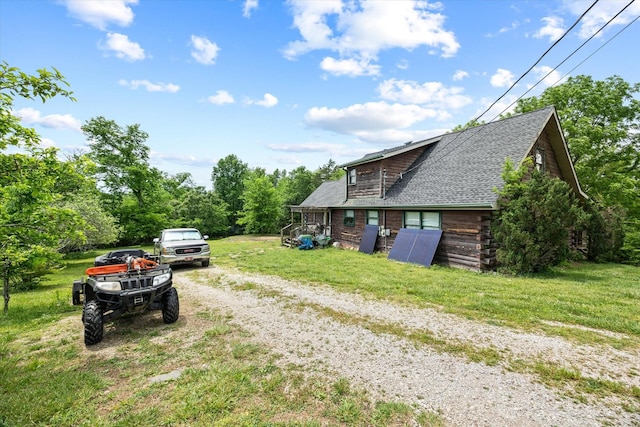 exterior space featuring a lawn, driveway, a shingled roof, and log siding