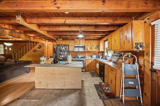 kitchen with a sink, wood ceiling, wood walls, beamed ceiling, and stainless steel appliances