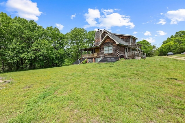 exterior space featuring log siding, a deck, a chimney, and a front yard