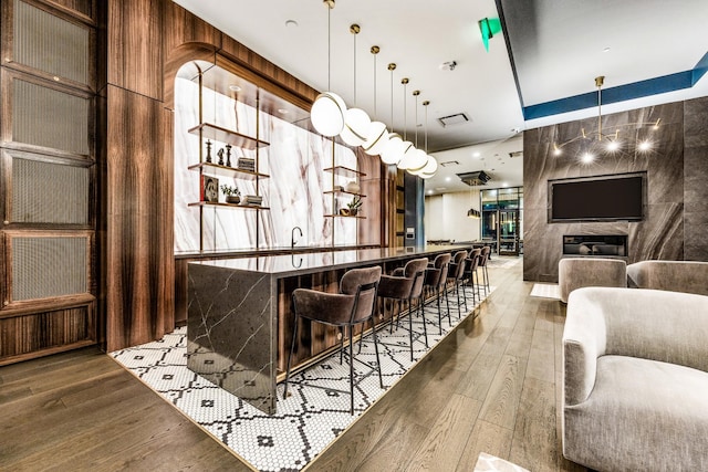 bar with a community bar, hanging light fixtures, visible vents, and wood finished floors