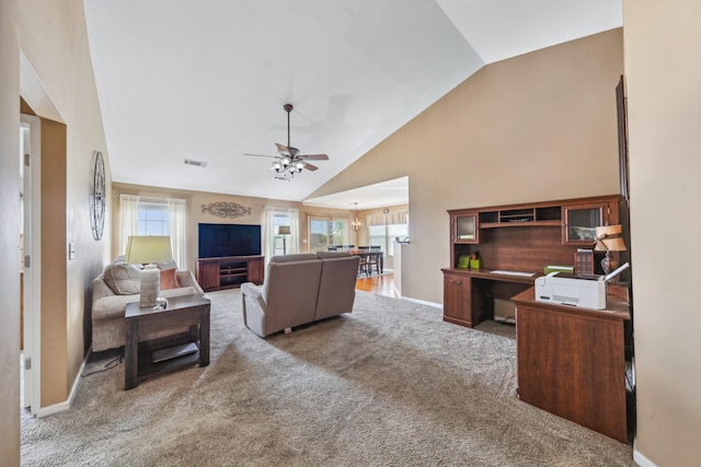 living area with ceiling fan with notable chandelier, high vaulted ceiling, visible vents, carpet floors, and baseboards