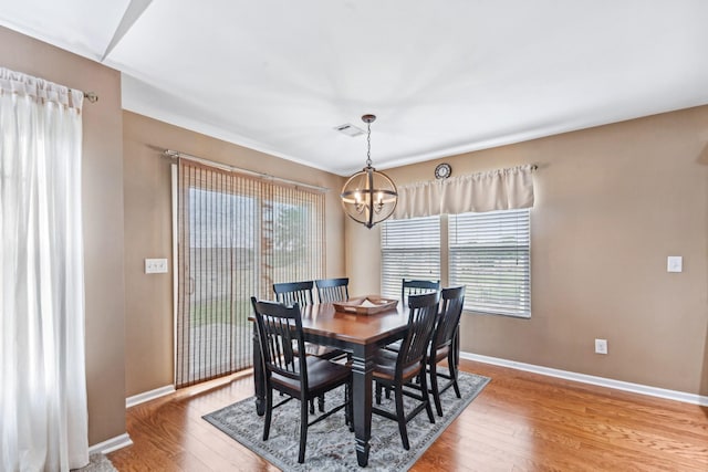 dining room with a chandelier, baseboards, light wood finished floors, and visible vents