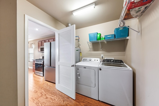 laundry area with washing machine and dryer, light wood finished floors, laundry area, and gas water heater