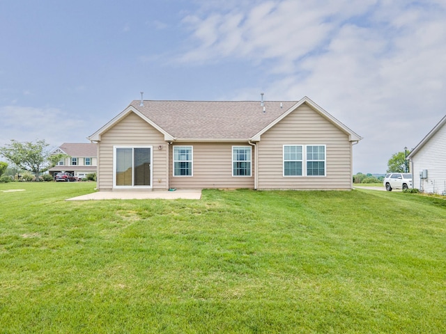 rear view of property with a lawn, a patio area, and a shingled roof