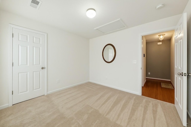 unfurnished bedroom with attic access, carpet floors, baseboards, and visible vents