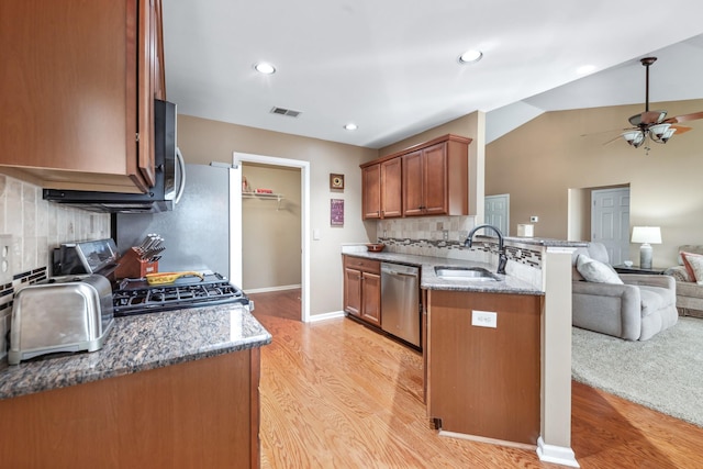 kitchen with light wood finished floors, dishwasher, open floor plan, and a sink