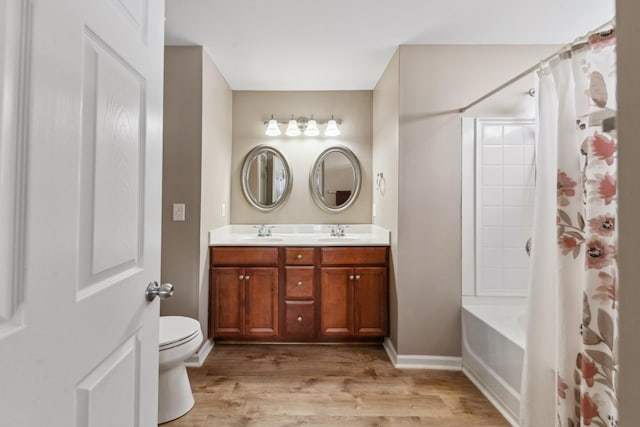 bathroom with a sink, double vanity, toilet, and wood finished floors
