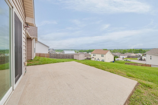 view of patio featuring a storage shed, an outbuilding, a residential view, and fence