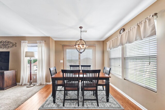 dining room with an inviting chandelier, light wood-style floors, visible vents, and baseboards