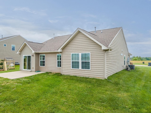 back of property with a lawn, cooling unit, a patio, and a shingled roof