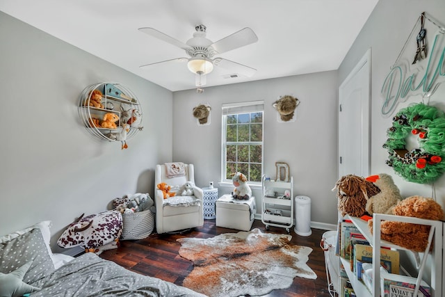 living area featuring baseboards, a ceiling fan, visible vents, and wood finished floors