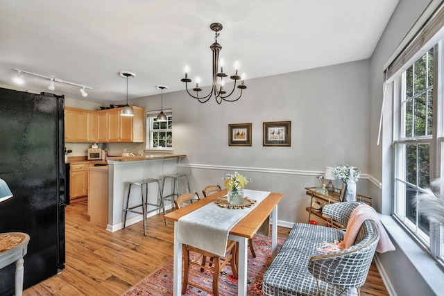 dining space featuring baseboards, an inviting chandelier, and light wood-style flooring