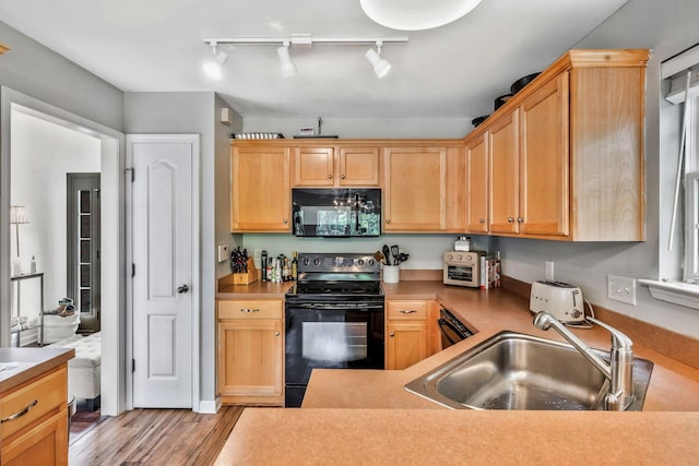 kitchen with track lighting, light brown cabinetry, black appliances, and a sink