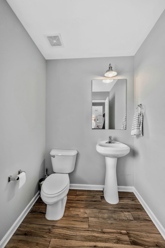 bathroom with toilet, baseboards, visible vents, and wood finished floors