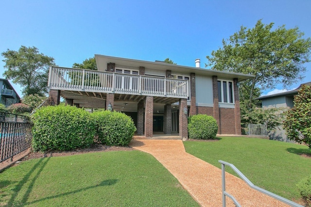rear view of property with a yard, a deck, brick siding, and fence