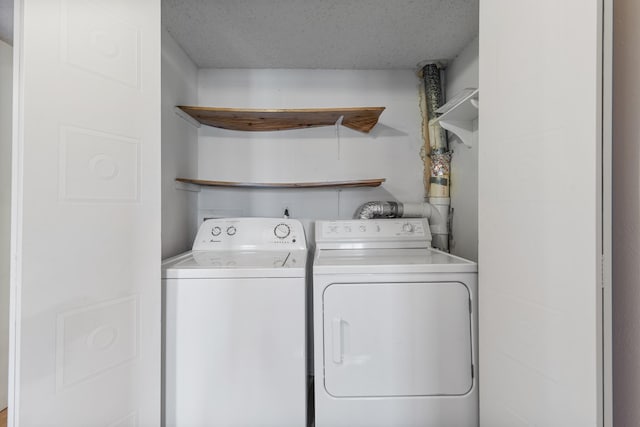clothes washing area with laundry area, a textured ceiling, and washer and clothes dryer