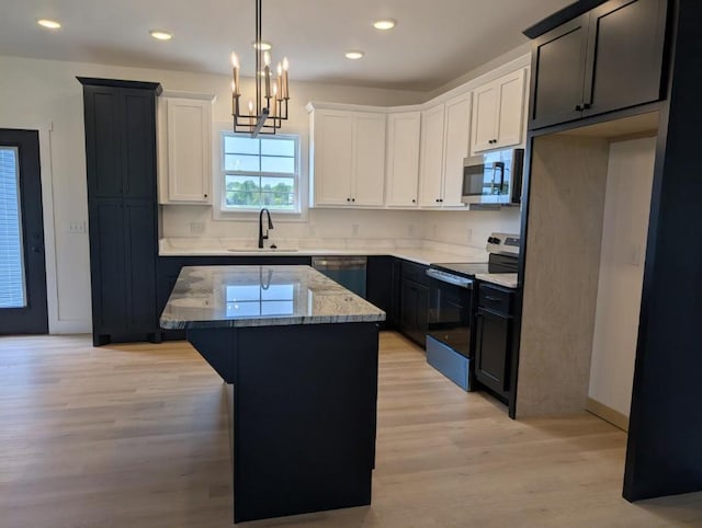 kitchen featuring a center island, light wood-style flooring, a sink, stainless steel appliances, and light stone counters