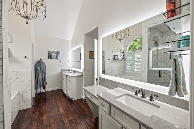 bathroom with a sink, wood finished floors, a shower stall, a notable chandelier, and a bath