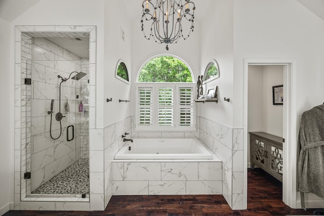 bathroom with an inviting chandelier, a bath, a shower stall, wood finished floors, and a high ceiling