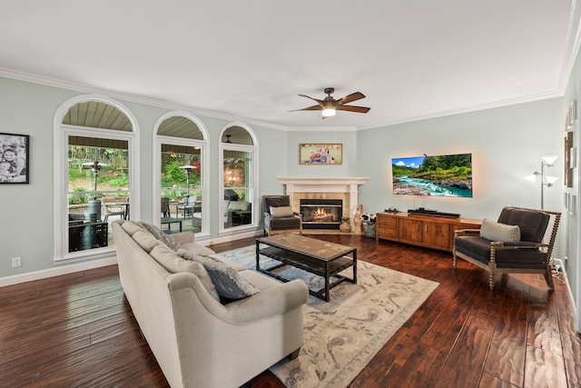 living room featuring a fireplace, ceiling fan, ornamental molding, and dark wood-type flooring