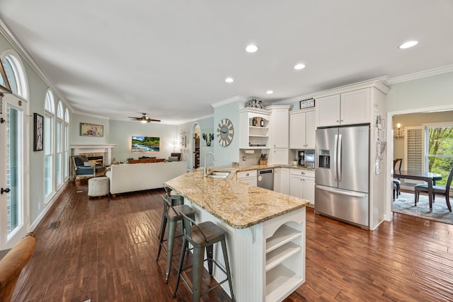 kitchen featuring a sink, a peninsula, stainless steel appliances, ornamental molding, and open shelves