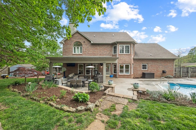 back of property featuring fence, a patio area, brick siding, a fenced in pool, and a chimney