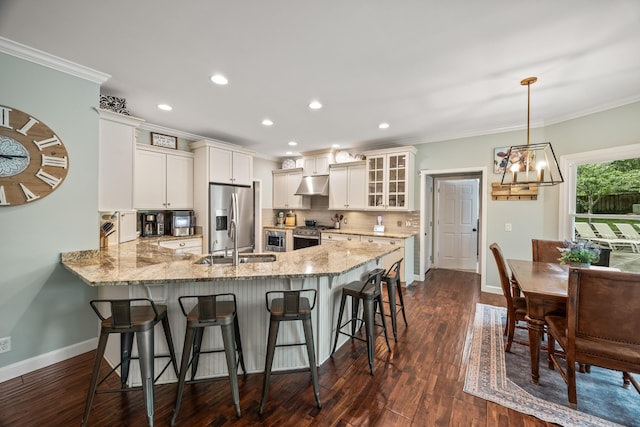kitchen with under cabinet range hood, crown molding, stainless steel appliances, and baseboards