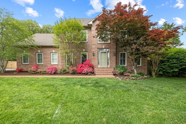 colonial inspired home featuring a front yard and brick siding