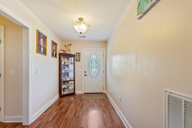 doorway to outside featuring baseboards, visible vents, and wood finished floors