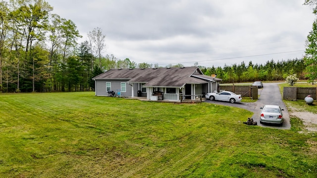 back of house with a yard, fence, and aphalt driveway