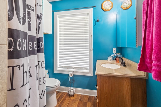 bathroom featuring baseboards, toilet, a shower with shower curtain, vanity, and wood finished floors