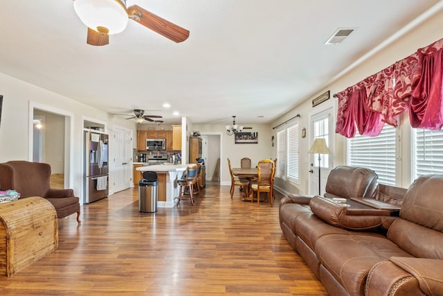 living room featuring recessed lighting, baseboards, visible vents, ceiling fan with notable chandelier, and wood finished floors