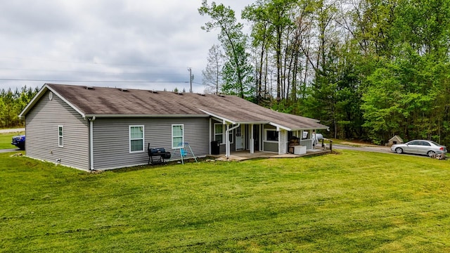 rear view of house featuring covered porch, roof with shingles, and a lawn