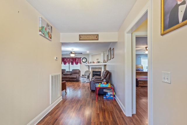 hall featuring baseboards, visible vents, and wood finished floors