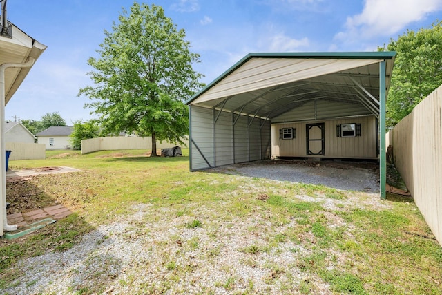 view of outdoor structure featuring fence, a carport, and driveway