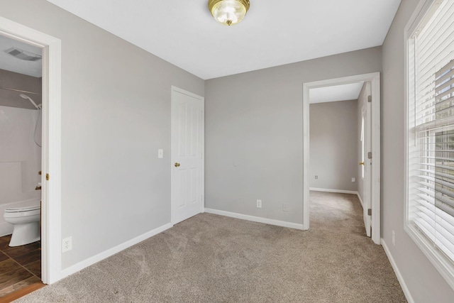 unfurnished bedroom with carpet flooring, ensuite bathroom, visible vents, and baseboards