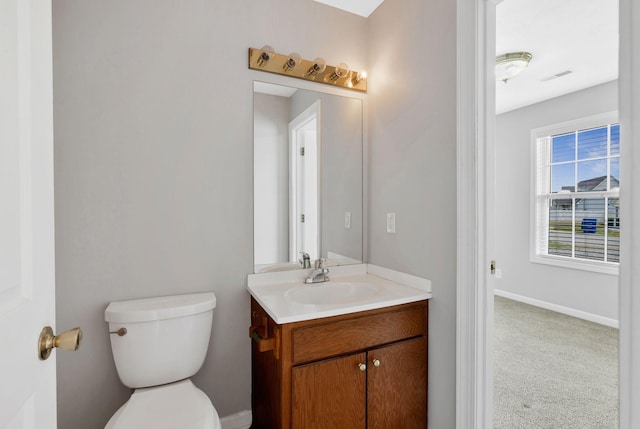 half bath featuring toilet, visible vents, baseboards, and vanity