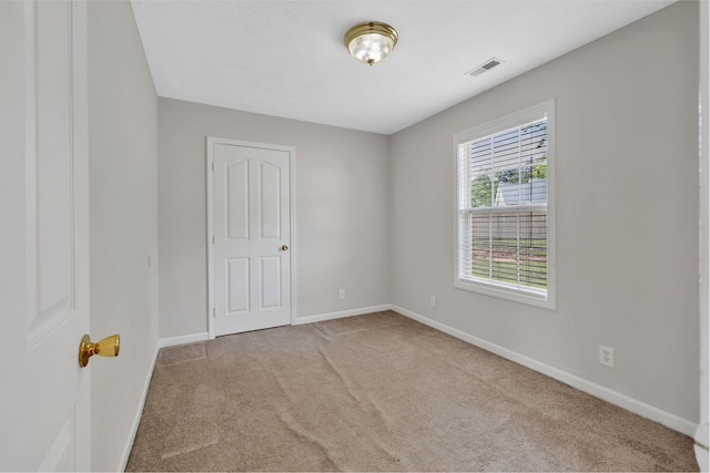 carpeted spare room featuring visible vents and baseboards