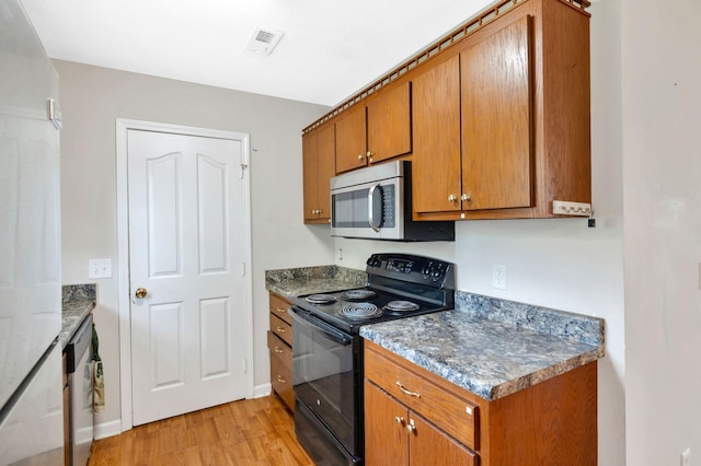 kitchen with brown cabinetry, light wood-type flooring, visible vents, and appliances with stainless steel finishes