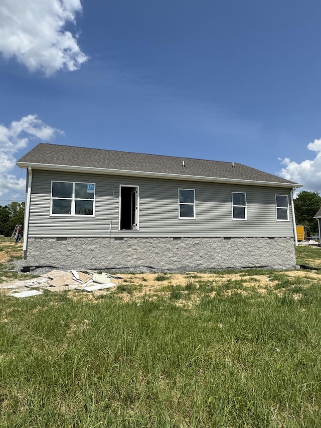 rear view of property featuring a lawn and crawl space
